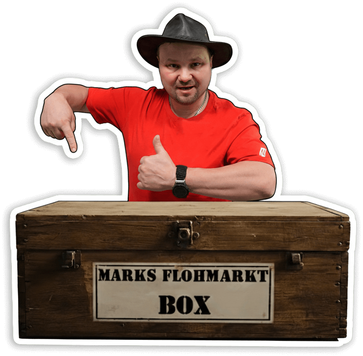 Mark Molter mit Hut, der auf seine bekannte Flohmarkt-Box zeigt